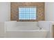 A bright white bathtub with vintage floral wallpaper and block window providing natural light at 905 Star Pine Dr, Las Vegas, NV 89144