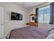 Bright bedroom featuring a large window, dresser with mirror, and flat-screen TV at 9950 Coyote Echo Ct, Las Vegas, NV 89166