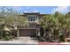 Charming two-story home showcasing a well-manicured yard with mature trees, a neutral color palette, and an attached two-car garage at 9950 Coyote Echo Ct, Las Vegas, NV 89166