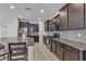 Modern kitchen featuring dark cabinetry, stainless appliances, tile backsplash, and a granite island with barstool seating at 9950 Coyote Echo Ct, Las Vegas, NV 89166