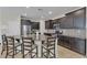 Contemporary kitchen featuring dark cabinets, stainless appliances, granite countertops, and an island with bar stool seating at 9950 Coyote Echo Ct, Las Vegas, NV 89166