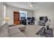 Spacious living room includes a comfortable gray couch, tall shelves, and an exercise bike by the window at 9950 Coyote Echo Ct, Las Vegas, NV 89166