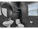 Stylish powder room featuring dark walls, a round mirror, and modern fixtures at 9950 Coyote Echo Ct, Las Vegas, NV 89166