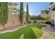 Backyard with artificial turf, complemented by lush greenery, a statue and string lights at 11417 Rock Cove Way, Las Vegas, NV 89141