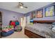 Comfortable bedroom with a ceiling fan, purple walls, and fun cartoon themed decor at 11417 Rock Cove Way, Las Vegas, NV 89141