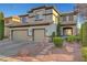 Two-story home with a three car garage, neutral stucco exterior with stone accents and desert landscaping at 11417 Rock Cove Way, Las Vegas, NV 89141