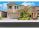 Charming tan two-story home featuring a brick driveway, stucco exterior, well-manicured landscaping, and an attached two-car garage at 152 Walkinshaw Ave, Las Vegas, NV 89148