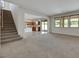 Open-concept living room with staircase, kitchen view, and ample natural light at 152 Walkinshaw Ave, Las Vegas, NV 89148