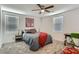 Cozy bedroom with a bed, ceiling fan, two windows, a desk, and carpeted floors at 1611 Prairie Fields Ct, Las Vegas, NV 89115