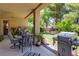 Covered patio area with a grill, seating, and a well-maintained backyard with green trees at 2026 Poppywood Ave, Henderson, NV 89012