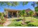 Landscaped backyard featuring green grass, small trees, and a covered patio at 2026 Poppywood Ave, Henderson, NV 89012