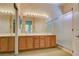 Bright bathroom featuring dual sinks, large mirror, wood cabinets, and a glass shower door at 2026 Poppywood Ave, Henderson, NV 89012