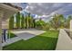 Spacious backyard featuring artificial grass, mature trees, and a concrete pad for outdoor activities at 2058 Troon Dr, Henderson, NV 89074