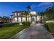 Elegant two-story home features a meticulously landscaped yard, a stately entrance, and a circular driveway at dusk at 2058 Troon Dr, Henderson, NV 89074