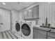 Bright laundry room with front-loading washer and dryer, countertop, and geometric tile flooring at 2058 Troon Dr, Henderson, NV 89074