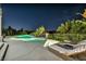 Luxurious pool area features a relaxing spa, comfortable lounge chairs, and lush landscaping under the night sky at 2058 Troon Dr, Henderson, NV 89074