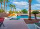 Backyard featuring a swimming pool with a rock slide, palm trees, and a lounging area at 268 Copper Glow Ct, Henderson, NV 89074