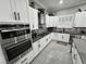 Well-equipped kitchen featuring stainless steel appliances, sleek white cabinetry, and patterned backsplash tiles at 2891 S Rainbow Ave, Pahrump, NV 89048