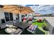 Outdoor dining and lounge area on artificial turf with patio furniture under a shaded umbrella, ideal for entertaining guests at 2891 S Rainbow Ave, Pahrump, NV 89048