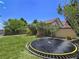Well-manicured lawn in backyard with a trampoline and greenery around the block wall at 396 Blackstone River Ave, Las Vegas, NV 89148