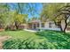 Private backyard features lush artificial turf, covered patio, mature trees, and partial fencing at 42 Glade Water Dr, Henderson, NV 89052