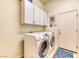Functional laundry room equipped with a front load washer and dryer, and overhead cabinets at 42 Glade Water Dr, Henderson, NV 89052