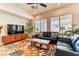 Spacious living room with a colorful rug, modern furniture, and abundant natural light through shuttered windows at 42 Glade Water Dr, Henderson, NV 89052