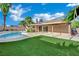 View of the backyard pool and covered patio space with artificial turf lawn at 4637 Balfour Dr, Las Vegas, NV 89121