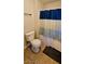 Efficient bathroom layout featuring a toilet, a shower with a blue and white curtain, and tile flooring at 5045 Bayberry Crest St, North Las Vegas, NV 89031