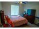 Cozy bedroom with orange themed comforter, matching nightstand and dresser, and a ceiling fan at 5216 Loma Verde Ave, Las Vegas, NV 89108