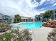 Resort-style community pool area with lounge chairs, rock features, and colorful flowering plants at 6955 N Durango Dr # 1022, Las Vegas, NV 89149
