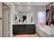 Bathroom featuring dual vanity, tub, black and white striped wallpaper, and large mirror for a modern aesthetic at 7109 Red Gulch St, North Las Vegas, NV 89084