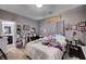 Cluttered bedroom with eclectic decor, bed with patterned bedding, and a door to the bathroom at 7109 Red Gulch St, North Las Vegas, NV 89084
