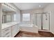 Bright bathroom with double sinks, a soaking tub, a glass-enclosed shower, and stylish lighting at 7606 Kenwood Hills Ct, Las Vegas, NV 89131