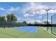 Well-maintained tennis court with blue and green surface, surrounded by fencing and lighting, on a partly cloudy day at 7606 Kenwood Hills Ct, Las Vegas, NV 89131