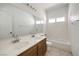 Bright bathroom with double sinks, large mirror and tiled shower and floors at 7977 Blue Brook Dr, Las Vegas, NV 89147