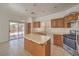 Bright kitchen with oak cabinets, a center island, tile flooring, and stainless steel appliances at 7977 Blue Brook Dr, Las Vegas, NV 89147