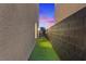 Narrow backyard features artificial grass area, with block wall and stucco house border on either side at 8055 Haywood Estate Ave, Las Vegas, NV 89113