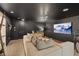 Dark living room featuring a large sectional couch, accent lighting, and modern entertainment setup, offering a cozy atmosphere at 8055 Haywood Estate Ave, Las Vegas, NV 89113