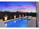 Backyard swimming pool with sleek design, submerged seating, decorative planters, and ambient lighting for stylish outdoor living at 8055 Haywood Estate Ave, Las Vegas, NV 89113
