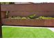 Spacious backyard featuring artificial grass, greenery, and a brick fence at 8131 Skye Plum St, Las Vegas, NV 89166