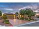 Well-maintained home featuring a two-car garage, landscaped yard, and warm exterior lighting at 8633 Kennedy Heights Ct, Las Vegas, NV 89131