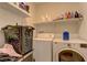 Convenient laundry room featuring a washer, dryer, and shelving for storage at 9091 Jumping Jacks Ave, Las Vegas, NV 89178