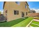 Exterior view of a home's backyard featuring green turf and the building's facade at 934 Twincrest Ave, North Las Vegas, NV 89032