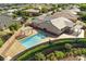 Aerial view displays a backyard oasis with a refreshing pool, adjacent spa, covered patio, and green landscaping at 10302 Artful Stone Ave, Las Vegas, NV 89149