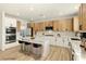 Modern kitchen features stainless steel appliances, light wood cabinets, and island with white countertop and bar stool seating at 10302 Artful Stone Ave, Las Vegas, NV 89149