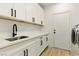 Well-organized laundry room with white cabinets, quartz counters, a stainless-steel sink, and a modern washer at 10302 Artful Stone Ave, Las Vegas, NV 89149