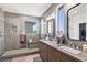 Modern bathroom featuring a double vanity, large mirrors, and a glass shower at 10368 Mystic Pine Rd, Las Vegas, NV 89135