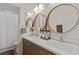 Stylish bathroom featuring dual sinks, modern wood cabinets, three round mirrors, and elegant fixtures at 10368 Mystic Pine Rd, Las Vegas, NV 89135