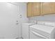 Well-lit laundry room with a washer, dryer, white door, and storage cabinets above units at 1063 Silver Star St, Henderson, NV 89002